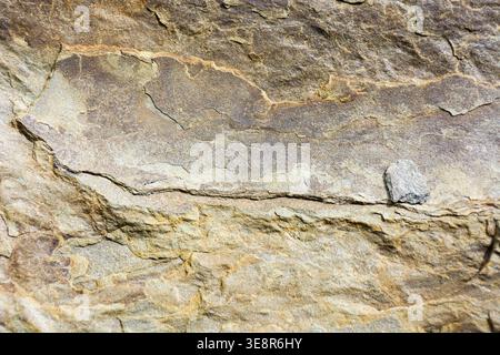 grunge texture of yellowish gray stone. natural rock background shot outside. aged matte patterns of sandstone with subtle cracks Stock Photo