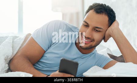 Man Relaxing in Bed While Using a Smartphone During a Quiet Morning at Home Stock Photo