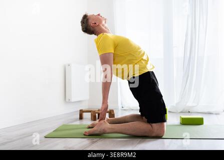 Sporty Young Man Doing Yoga Routine Practice, Standing In Camel Pose Stock Photo