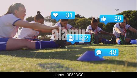 Stretching five female soccer players on school field in team kits and cleats, blue cone overlays Stock Photo