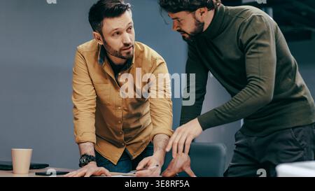 Two Men Discussing Project Details in a Modern Office During a Work Meeting Stock Photo