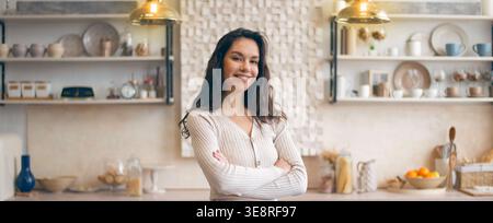 A Young Woman Smiles While Standing in a Kitchen Stock Photo