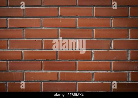 Weathered brick wall with mortar lines, even lighting highlights rough texture and red tonal variation, horizontal bond Stock Photo