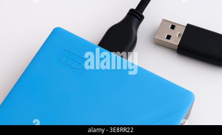 Tambov, Russian Federation - July 19, 2021 Blue WD My Passport external hard drive with a black USB cable on a white background. Close-up. Stock Photo