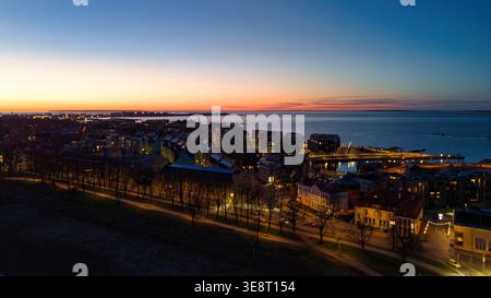 Aerial view of the coastline at twilight with illuminated buildings ...