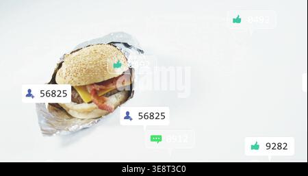 Displaying bacon cheeseburger in crinkled foil on white tabletop with social badges, copy space Stock Photo