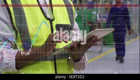 Inspecting worker wearing hi-vis vest and necktie, tapping tablet with data overlay in warehouse Stock Photo