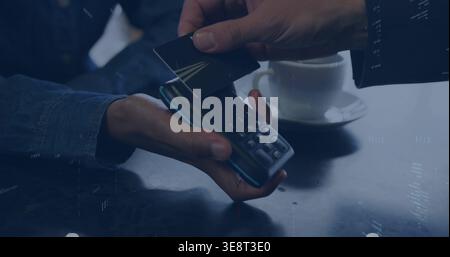 Tapping contactless card, denim-sleeve staff holding POS at cafe table, white cup on dark surface Stock Photo
