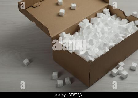 Cardboard box and styrofoam cubes on wooden floor Stock Photo