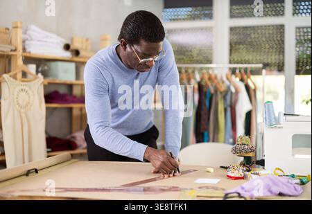 African American man tailor draw dress pattern on paper. Craftsman ...