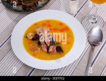 Plate of hearty pea soup with smoked meat served with bread Stock Photo