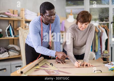 Two sewing workshop workers draw patterns on paper Stock Photo