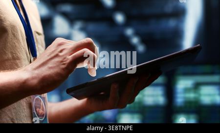 System administrator checking energy efficient supercomputers using renewable sources to minimize consumption and reduce business carbon footprint. Expert working in sustainable data center, close up Stock Photo