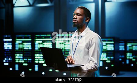 African american specialist in high tech establishment mending network problems affecting server clusters performance and connectivity, leading to slow data transfer rates Stock Photo