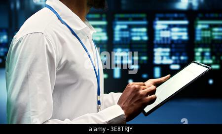 Technician inspecting server rigs hosting websites and delivering web content to clients over the internet. Professional using checklist to take note of critical systems, looking for potential issues Stock Photo