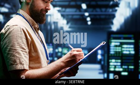 Supervisor monitoring energy efficient servers using renewable sources to minimize consumption and reduce overall facility carbon footprint. Technician working in eco friendly data center Stock Photo