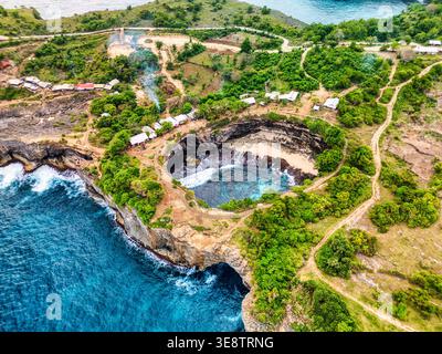 Aerial view of Broken Beach featuring the iconic circular rock formation and turquoise water surrounded by lush green cliffs in Nusa Penida, Bali, Ind Stock Photo