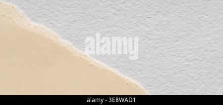 Two textured paper sheets with torn deckled edge overlap on cream and white background Stock Photo