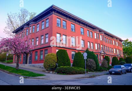 1010 Salsbury Drive Apartments with a cherry blossom to the side in East Vancouver, BC. Stock Photo