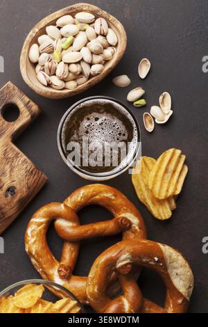 Lager beer and snacks on stone table. Nuts, chips, pretzel. Top view Stock Photo