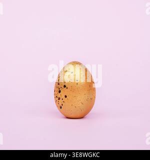 Golden easter egg with black spots on a pink background squared Stock Photo