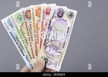 Old Philippine money - peso in the hand on a gray background Stock Photo
