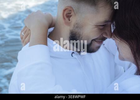 Loving couple on the sea. Tender relationship between a man and a woman. Ordinary people show love to each other. Happy couple hugging and kissing. Fa Stock Photo