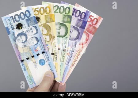 Philippine money - Peso in the hand on a gray background Stock Photo