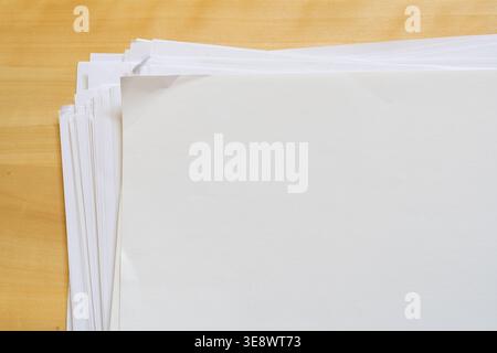 Close Up Stack of Blank White Paper Sheets on Wooden Desk Surface Stock Photo