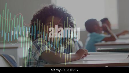 Smiling curly student wearing plaid shirt leaning on desk in classroom, pencil and data overlay Stock Photo