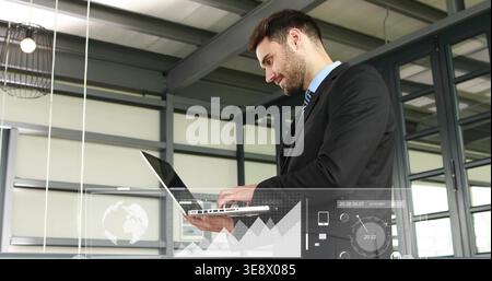 Holding businessman in dark suit typing on laptop in modern office, with virtual charts, copy space Stock Photo