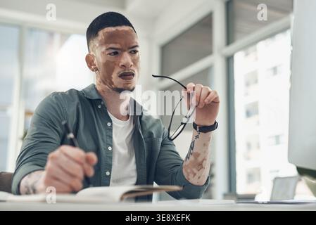 Creative, businessman and thinking with notebook in office, notes or copywriter with ideas for story. Serious, reflection and person with vitiligo Stock Photo
