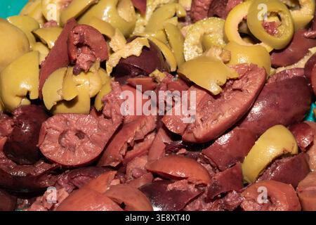 Sliced and chopped mixed olives on a blue background Stock Photo