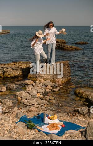 mother and daughter holding hands and walking on rocky beach, having picnic in weekend Stock Photo