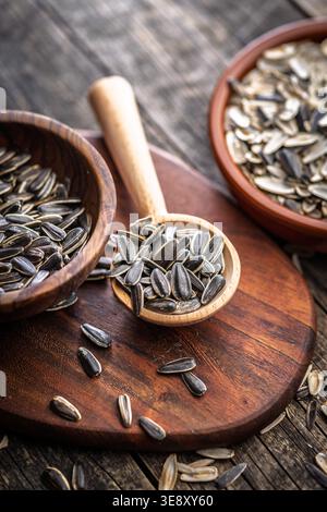 Sunflower seeds piled in a wooden spoon and bowls on a rustic cutting board, showing textured shells and natural tones. A healthy, crunchy snack and i Stock Photo