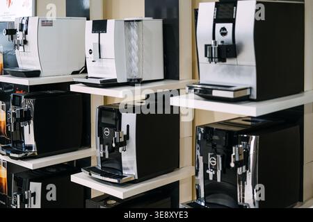 Row of professional JURA coffee machines stands on white shelves in showroom. JURA Coffee Machines, Luxury kitchen appliances, automatic espresso Stock Photo