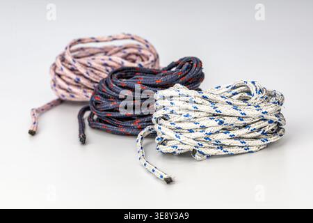 Three professionally arranged coiled braided nylon ropes featuring distinct color schemes: white with blue stripes, black with red accents, and gray w Stock Photo