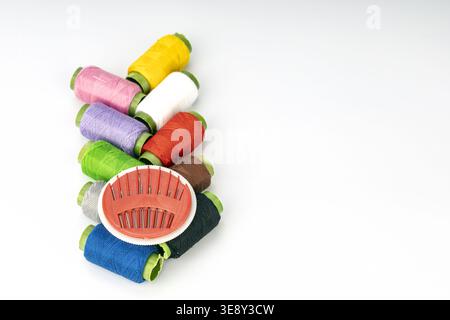 Neatly arranged embroidery thread spools in bright colors including yellow, pink, purple, white, red, green, gray, blue, and black with green thread h Stock Photo