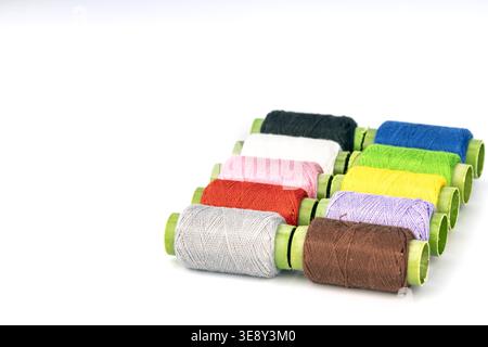 Professional arrangement of vibrant colored thread spools with distinctive green cardboard tubes. This comprehensive craft supply collection includes Stock Photo