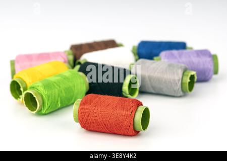 Professional assortment of colorful thread spools with bright green bobbins displayed on white background. Includes red, green, yellow, pink, brown, b Stock Photo