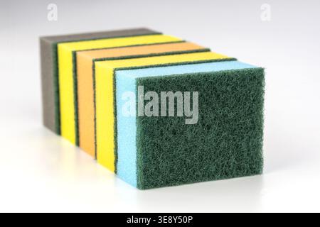Professional product photograph showing an organized stack of multicolor kitchen cleaning sponges with textured abrasive green scrubbing surfaces and Stock Photo