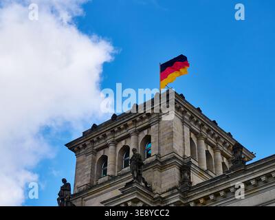 German Flag Waving on Reichstag Corner Tower Against Blue Sky, Berlin, Germany Stock Photo