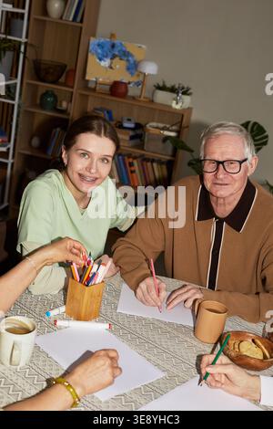 Portrait of senior Caucasian man with young adult female caregiver drawing during nursing home activity session Stock Photo