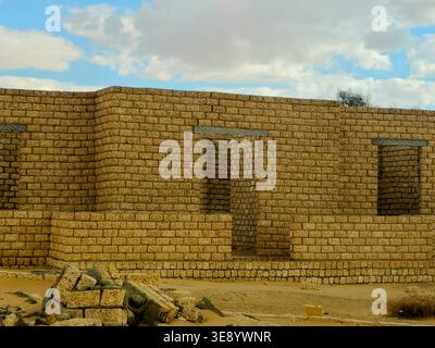 unfinished mud-brick walls of a building situated in a desert environment, the structure is built using compressed earth blocks or bricks made from so Stock Photo