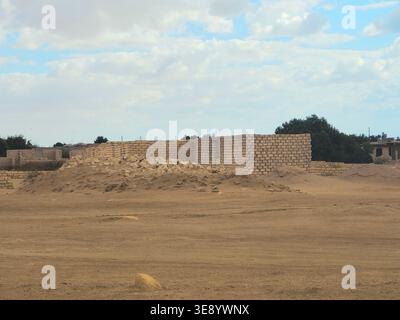unfinished mud-brick walls of a building situated in a desert environment, the structure is built using compressed earth blocks or bricks made from so Stock Photo