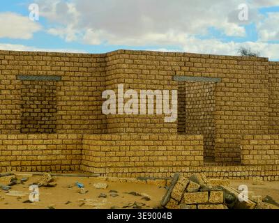unfinished mud-brick walls of a building situated in a desert environment, the structure is built using compressed earth blocks or bricks made from so Stock Photo