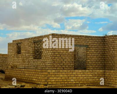 unfinished mud-brick walls of a building situated in a desert environment, the structure is built using compressed earth blocks or bricks made from so Stock Photo