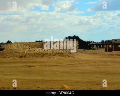 unfinished mud-brick walls of a building situated in a desert environment, the structure is built using compressed earth blocks or bricks made from so Stock Photo