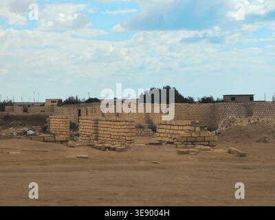 unfinished mud-brick walls of a building situated in a desert environment, the structure is built using compressed earth blocks or bricks made from so Stock Photo