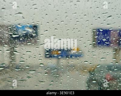 a view through a window covered in raindrops, during a storm or rainy day, The water droplets on the glass obscure the view, creating a blurred effect Stock Photo